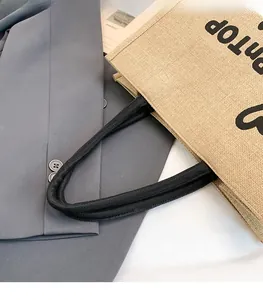 Detailed view of black rope handles on a textured jute burlap tote bag shopping