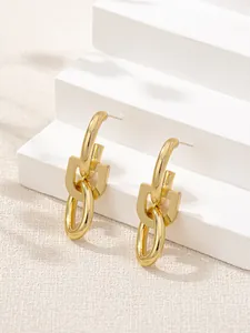 Close-up of elegant gold-plated geometric oval link drop earrings on white steps