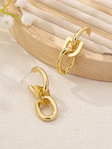 Detailed macro view of gold-tone linked oval drop earrings on wooden jewelry tray