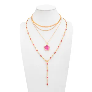 Détail d'un ensemble de colliers dorés à plusieurs rangs avec pendentif fleur rose