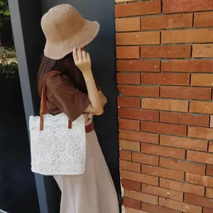 Detailansicht einer weißen Häkel-Strandtasche aus Spitze mit Lederriemen.