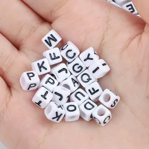 Primo piano di perline dell'alfabeto in cubo acrilico bianco con lettere nere in mano