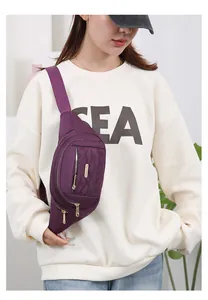 Detail of a purple multi-zipper waist bag for women, worn with a casual white sweatshirt.