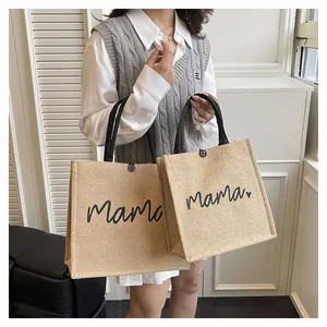 Detail of jute tote bags with 'mama' print held by a model in a stylish indoor setting.