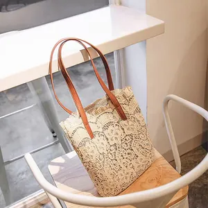 Elegante beige Spitzen-Strandtasche mit braunen Trägern auf einem weißen Stuhl Detail