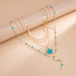 Détail du collier multicouche doré avec pendentif fleur bleue et cristaux colorés