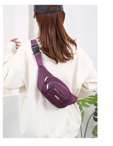 Detail showing purple multi-layer fanny pack worn as a crossbody bag on white sweater