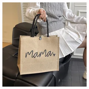 Detailed view of a natural jute tote bag with black Mama print and heart motif.