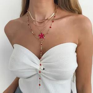 Vue détaillée d'un collier doré multi-rangs chic avec fleur rose et cristaux rouges