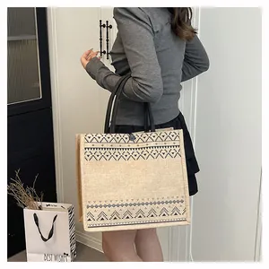 Macro view of a large capacity burlap tote bag featuring black geometric ethnic patterns