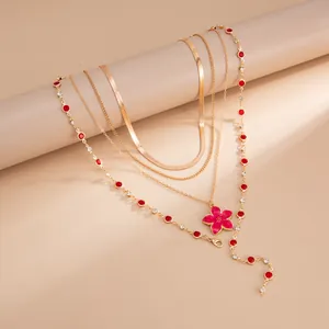 Vue détaillée du collier doré multicouche avec fleur en émail rouge et cristaux