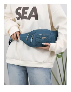 Close-up of a stylish teal multi-layered women's fanny pack worn across the waist.