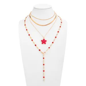 Vue détaillée du collier doré multicouche avec fleur en émail rouge et cristaux