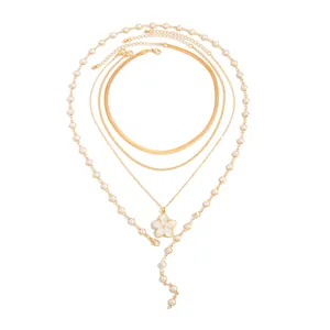 Détail d'un ensemble de colliers dorés avec pendentif fleur blanche et chaîne de perles