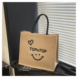 Perspective view of a durable jute tote bag with smiley print on a black surface