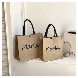Detailed macro view of natural burlap tote bags featuring stylish mama print and black handles
