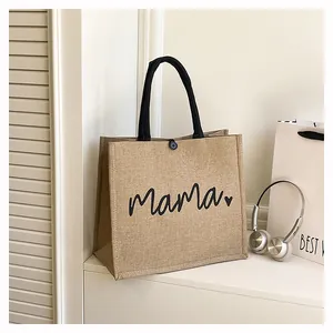 Detailed view of burlap tote bag with mama heart print and sturdy black handles.