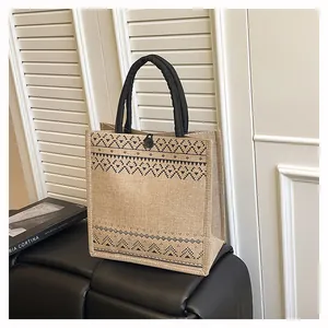 Eco-friendly jute tote bag with geometric print and black handles in a home setting