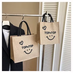 Detailed view of burlap tote bags with smiley face print hanging on a rack