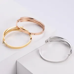 Close-up of three titanium steel bangles in gold, rose gold and silver finishes.