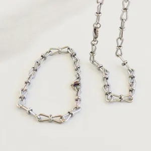 Detailed macro view of silver stainless steel bow-tie link chain necklace and bracelet jewelry set