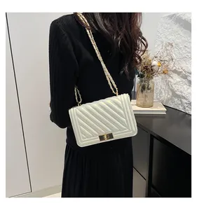 Close-up of pearl white quilted square crossbody bag featuring a gold chain strap