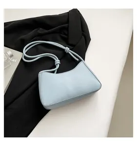 Top-down view of a light blue crescent shoulder bag with knotted strap on a black blazer