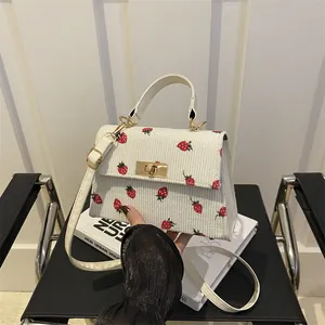 White corduroy shoulder bag featuring cute strawberry prints and gold clasp detail