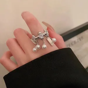 Nahaufnahme eines silbernen offenen Rings mit hängenden weißen Perlen und Zirkon-Details