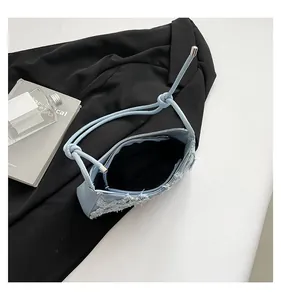 Interior view of a light blue denim underarm bag with stylish frayed denim edges