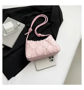 Close-up of pink denim underarm bag with frayed diamond texture and knotted strap