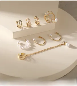 Primo piano di un set di orecchini a clip dorati con perle bianche e strass eleganti