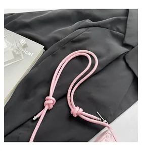 Close-up detail of a pink shoulder bag strap featuring stylish knotted design and metal tips