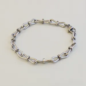 Detailed macro view of a silver stainless steel bracelet featuring elegant figure-8 knot links