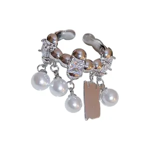 Eleganter versilberter offener Ring mit baumelnden weißen Perlen und Metallanhänger