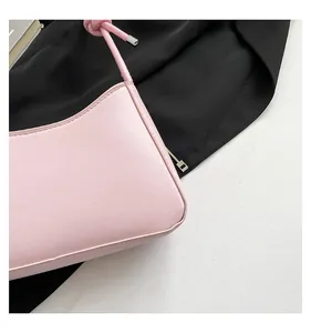 Detailed close-up view of a stylish light pink faux leather underarm baguette bag