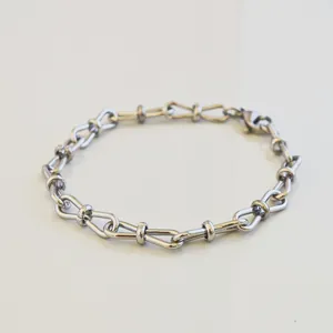 Close-up of a minimalist stainless steel 8-link chain bracelet on a white surface