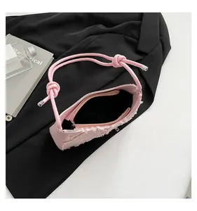 Detail view of pink denim underarm bag with fringe showing interior and zipper pocket