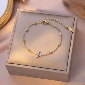 Elegante goudkleurige titaniumstalen armband met fonkelende klavertje vier kristallen bedel