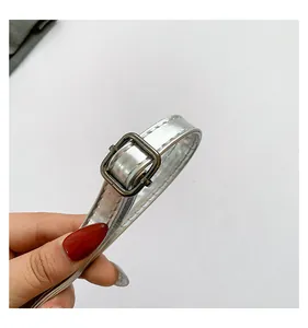 Dettaglio ravvicinato della tracolla argento metallizzato con fibbia in metallo.