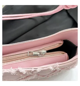 Close-up detail of pink denim underarm bag showing interior zipper and fringe texture