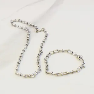 Elegant stainless steel interlocking 8-link necklace and bracelet set on marble