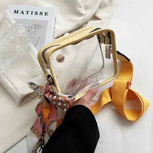 Détail d'un sac bandoulière transparent en PVC avec bordure jaune et foulard en soie