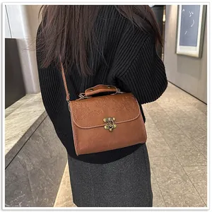 Vintage bruine leren vierkante tas met reliëf, gedragen als een elegante crossbodytas