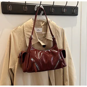Burgunderrote glänzende Lackleder-Motorradtasche, präsentiert an einem schicken Trenchcoat.