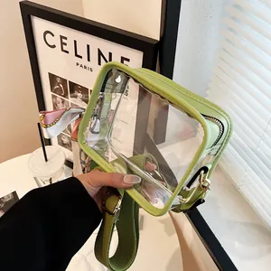 Gros plan d'un sac à bandoulière en PVC transparent bordé de vert avec foulard en soie.