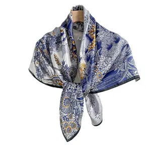 Elegant mulberry silk scarf with blue and white floral print hanging on a hanger
