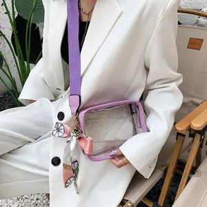 Détail rapproché du sac en PVC transparent avec large bandoulière violette et nœud