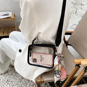 Détail d'un sac bandoulière en PVC transparent avec sangle noire et accessoire foulard.