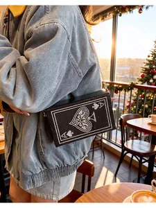 Vue détaillée d'un sac bandoulière noir orné de strass avec un motif de carte à jouer l'As de Pique.